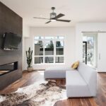 Modern metal and wood ceiling fan in a contemporary living space with tv and white couch