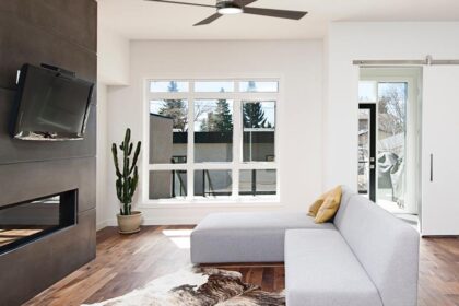 Modern metal and wood ceiling fan in a contemporary living space with tv and white couch