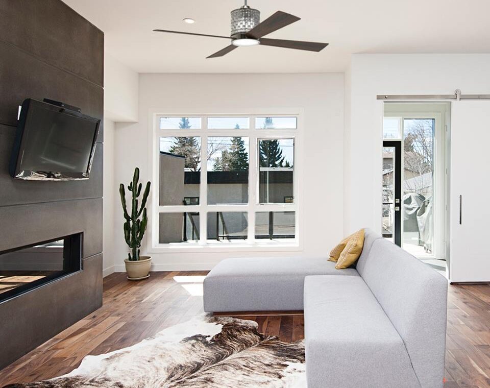 Modern metal and wood ceiling fan in a contemporary living space with tv and white couch